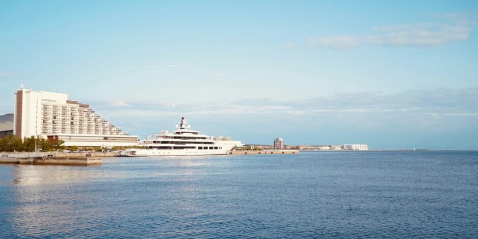 A yacht docks near a hotel and the ocean.