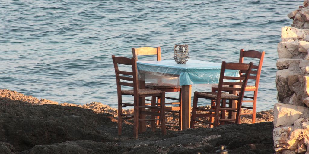 a table and chairs sitting on a rocky shore