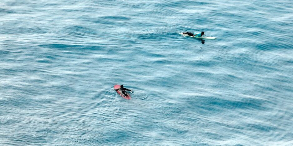 A couple of people riding on top of surfboards in the ocean