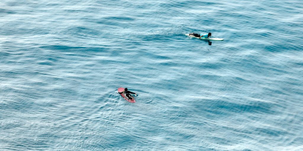 A couple of people riding on top of surfboards in the ocean